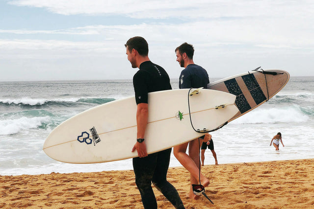 Surfistas yendo hacia la orilla de la playa